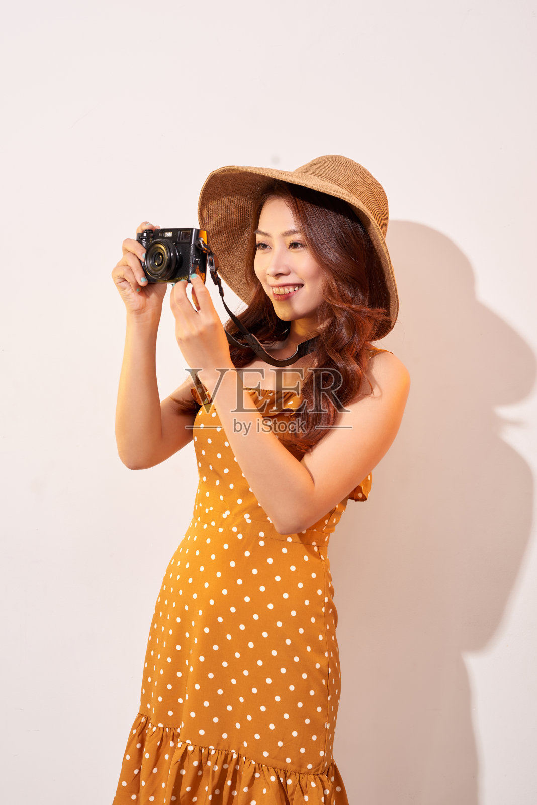 迷人的年轻女子与照片相机在她的手在孤立的米色背景。旅游的概念照片摄影图片