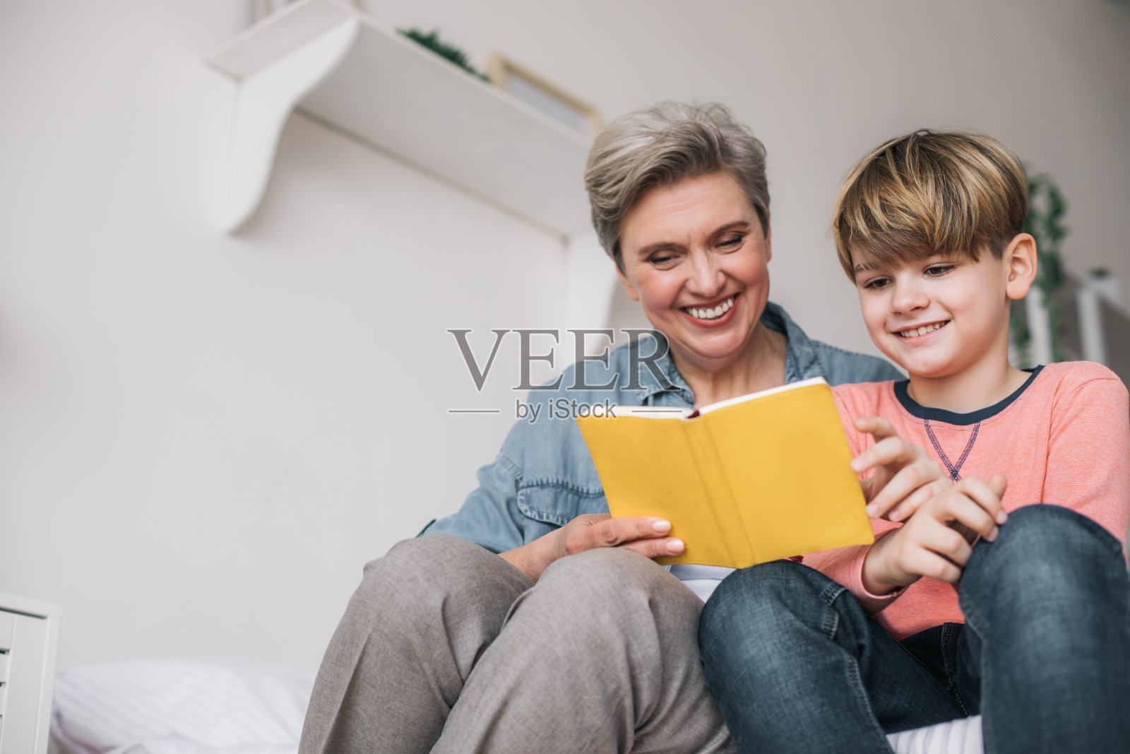 低角度的小男孩和他的祖母在房子里看书照片摄影图片