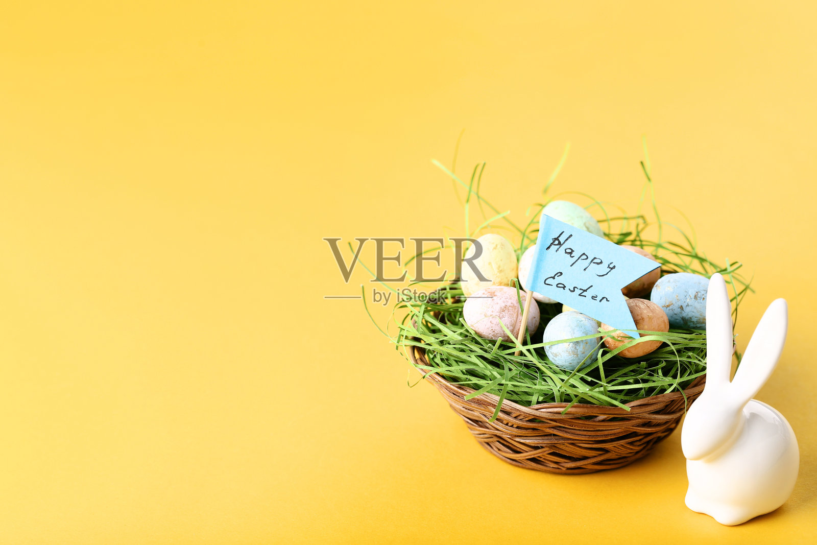 黄色背景的彩蛋上有白兔和“复活节快乐”字样照片摄影图片
