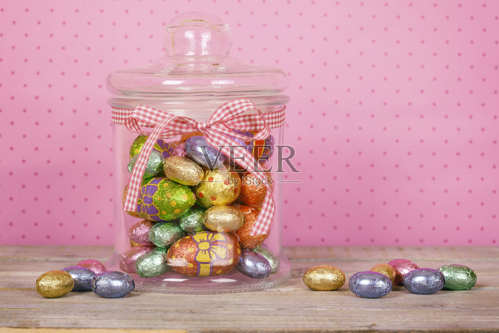 彩色巧克力复活节彩蛋玻璃罐在白色的木桌上。照片摄影图片