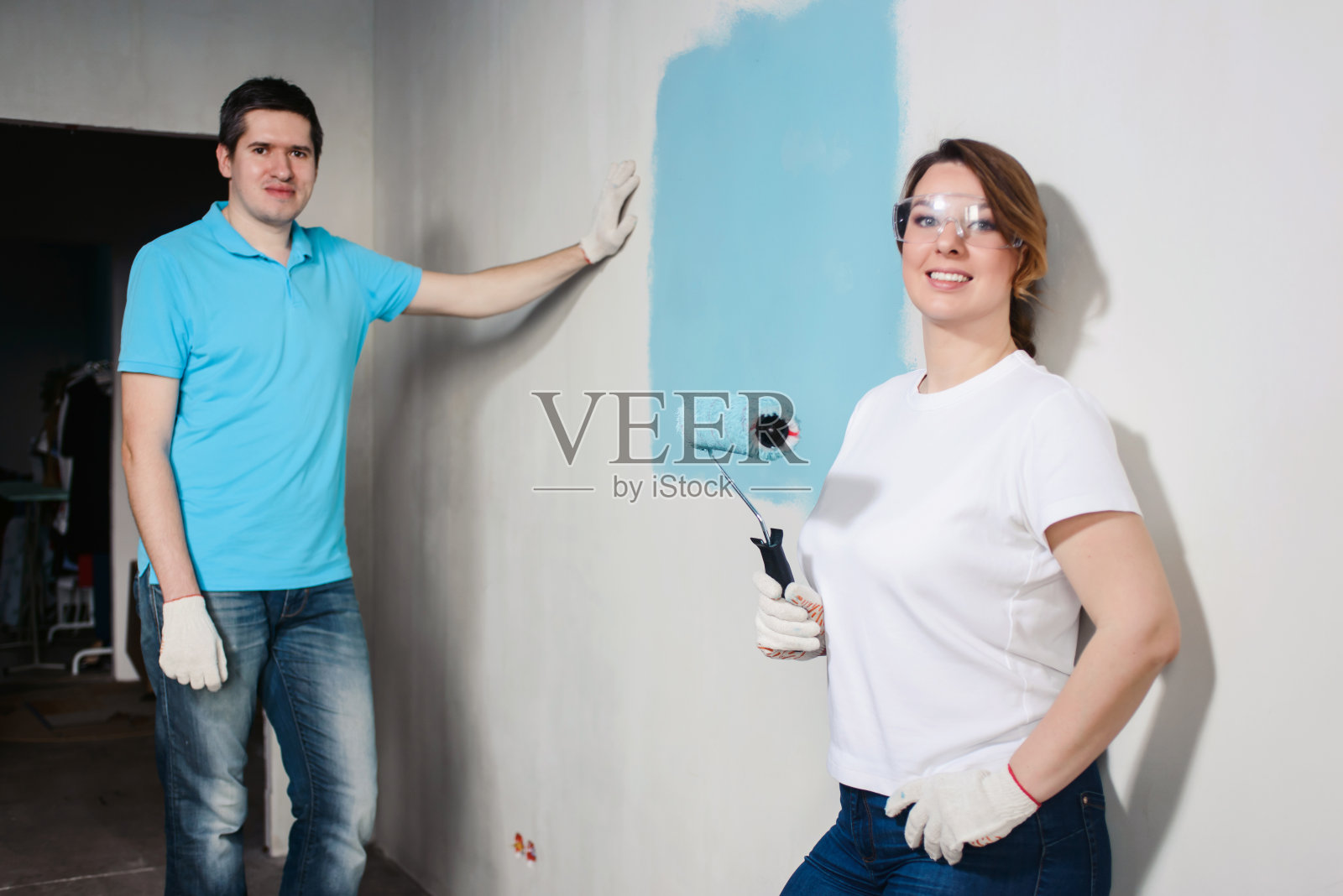 年轻幸福的夫妇油漆他们的新房子的内部使用油漆滚筒家庭改造和装修概念照片摄影图片