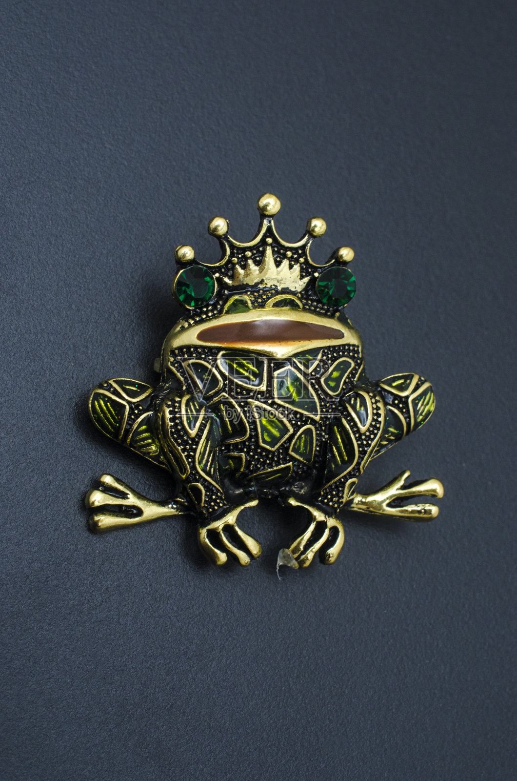 金色珐琅胸针青蛙戴着一个王冠孤立在黑色照片摄影图片