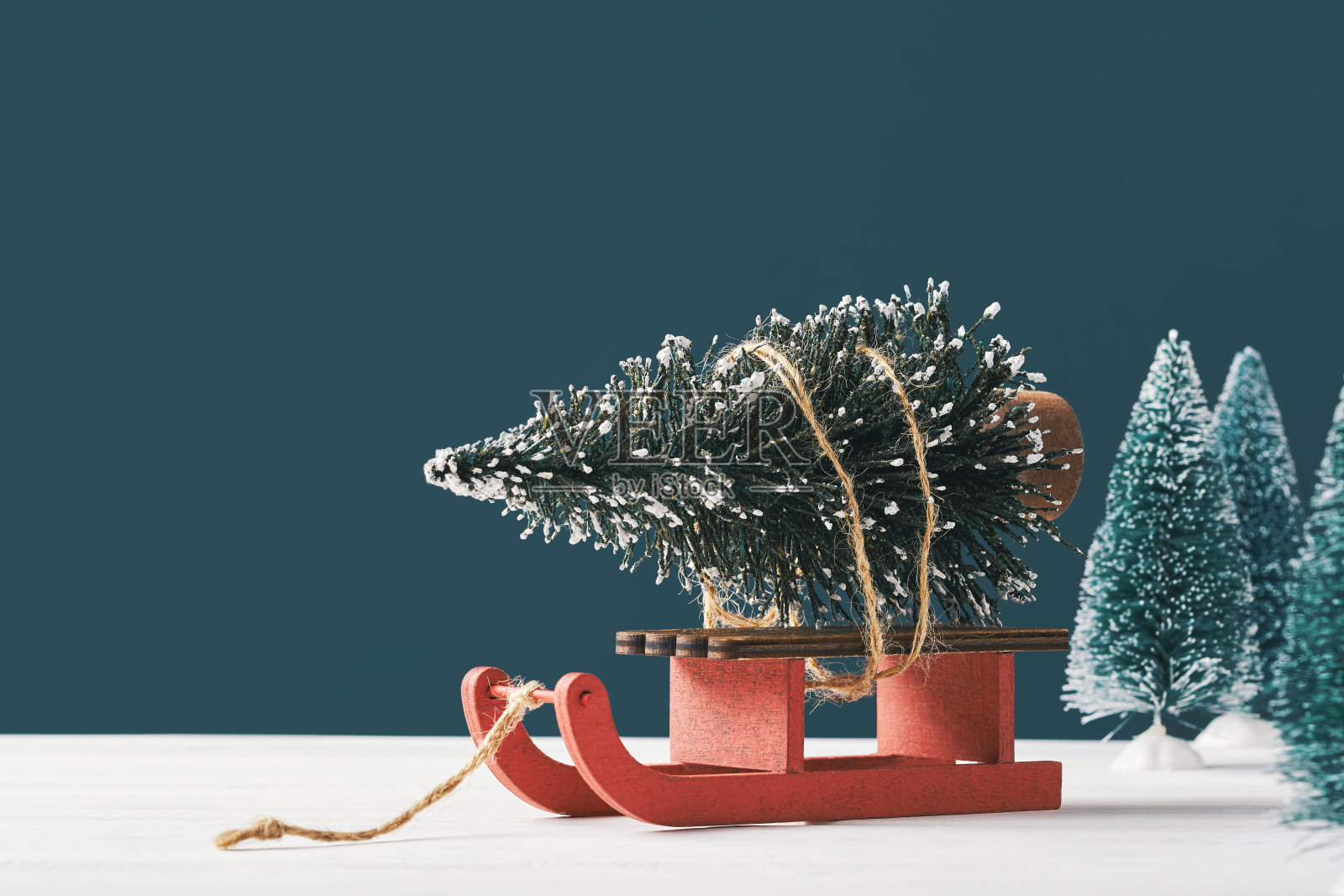 圣诞贺卡与你的文字的地方。一个明亮的圣诞树玩具的形式，冷杉树在圣诞老人的雪橇上，在黑暗的背景与玩具圣诞树的背景。下雪照片摄影图片