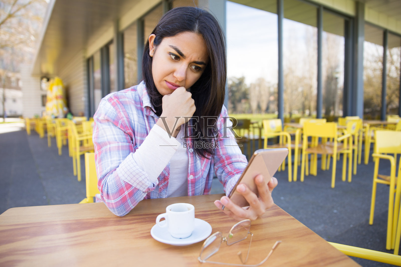 忧心忡忡的女人用着智能手机，在咖啡馆喝着咖啡照片摄影图片