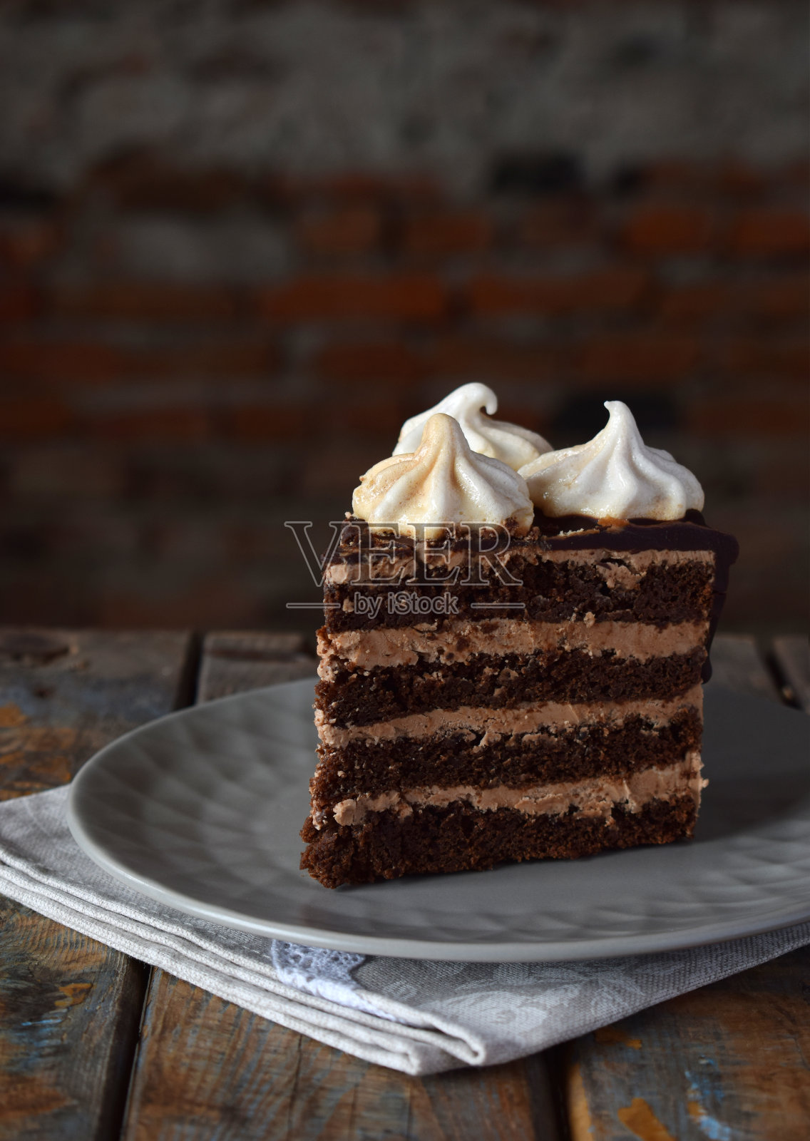 一块巧克力蛋糕，点缀着奶油蛋白花:巧克力坚果饼干，焦糖奶油。自制烘焙。照片摄影图片