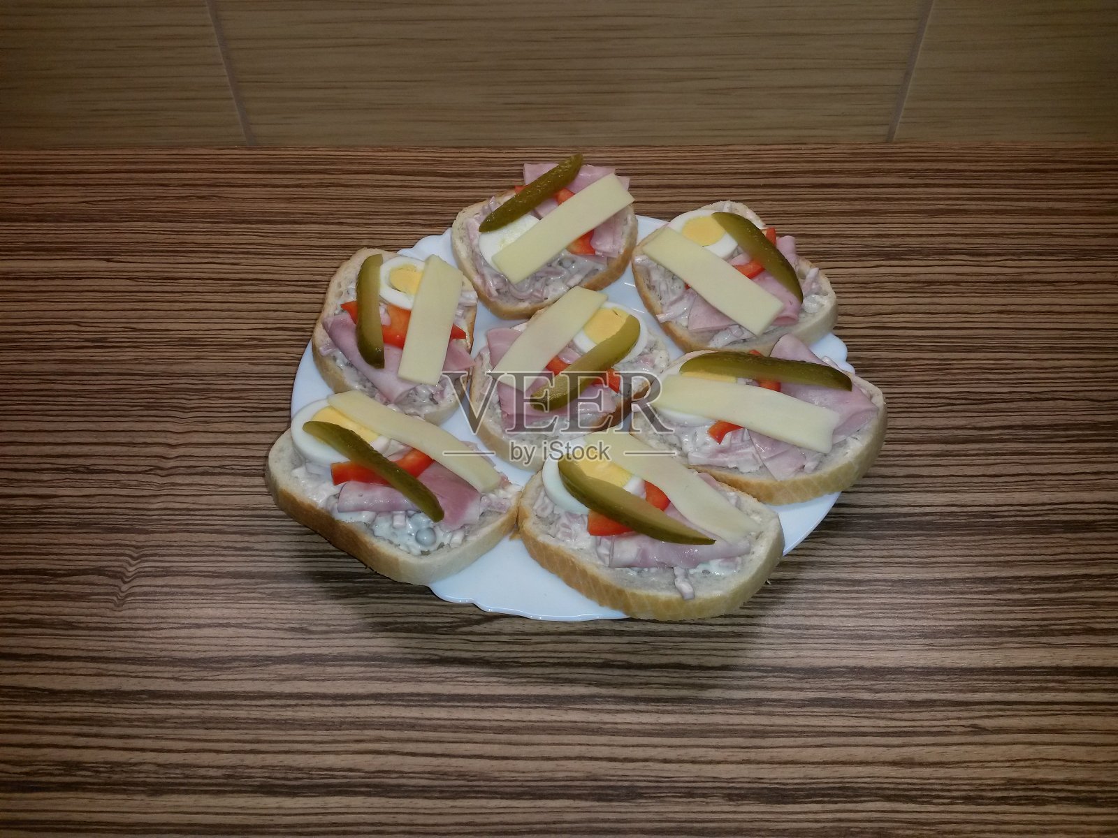 将三明治与沙拉，火腿，鸡蛋，奶酪，胡椒和黄瓜放在盘子里照片摄影图片