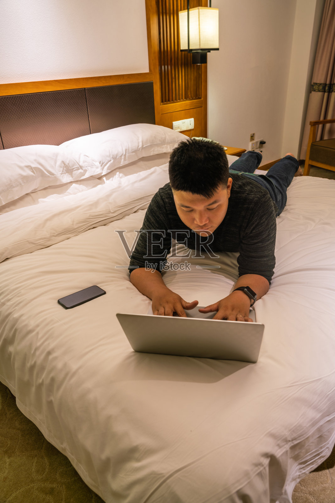 年轻人躺在床上使用笔记本电脑照片摄影图片
