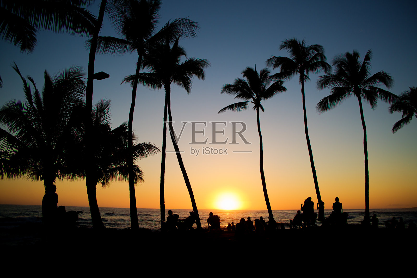 在考艾岛的普伊普海滩上，游客们在棕榈树下享受夏威夷日落照片摄影图片