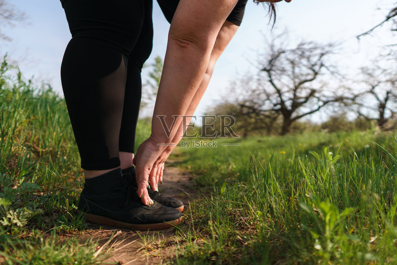 超重妇女跑步前热身腿。照片摄影图片