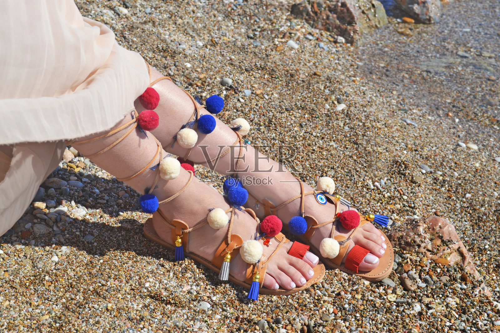 沙滩上的波西米亚希腊凉鞋和五颜六色的绒球广告照片摄影图片