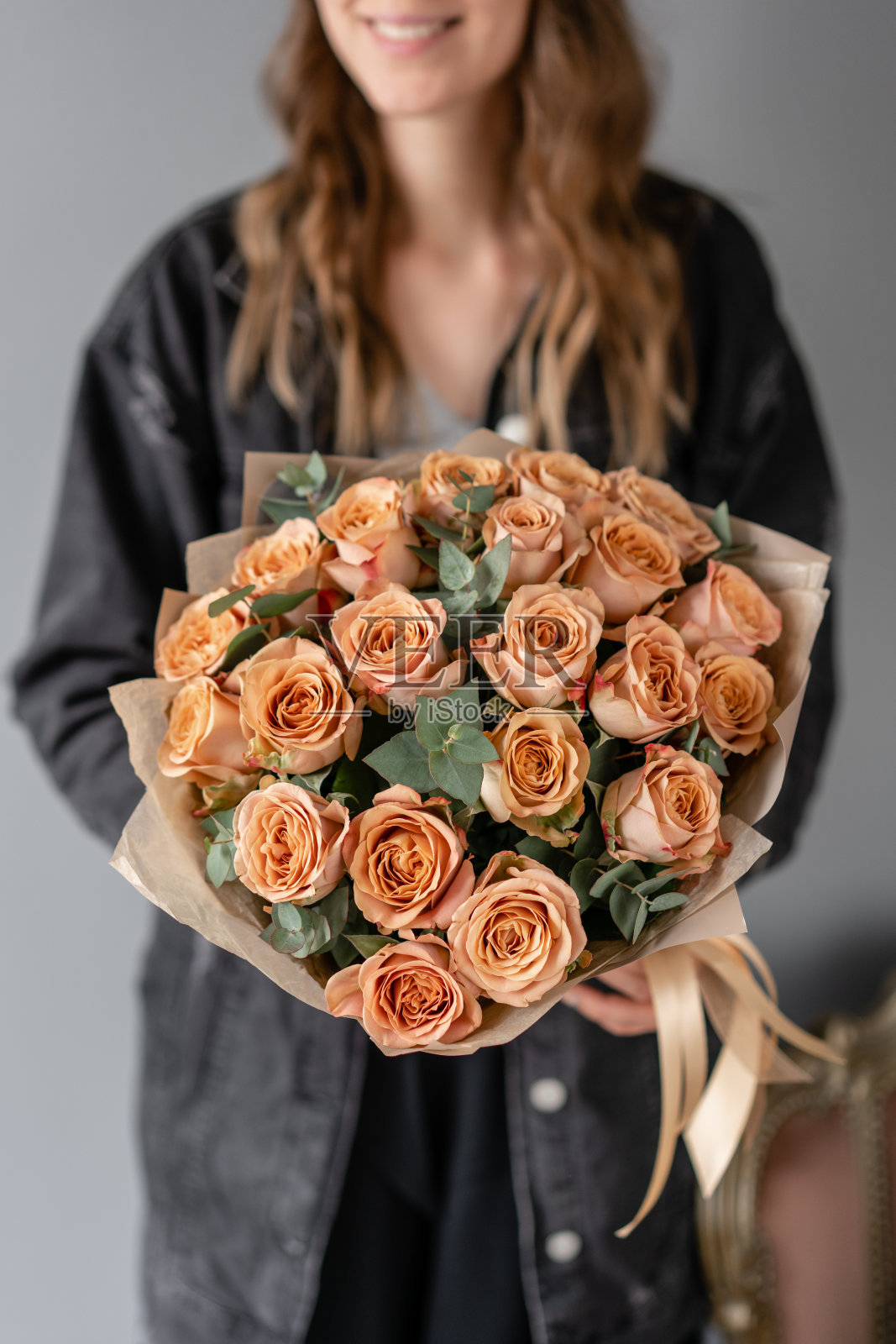 花朵咖啡色，卡布奇诺玫瑰加桉树。女人手里拿着漂亮的小花束。花卉商店的概念。鲜花交付照片摄影图片