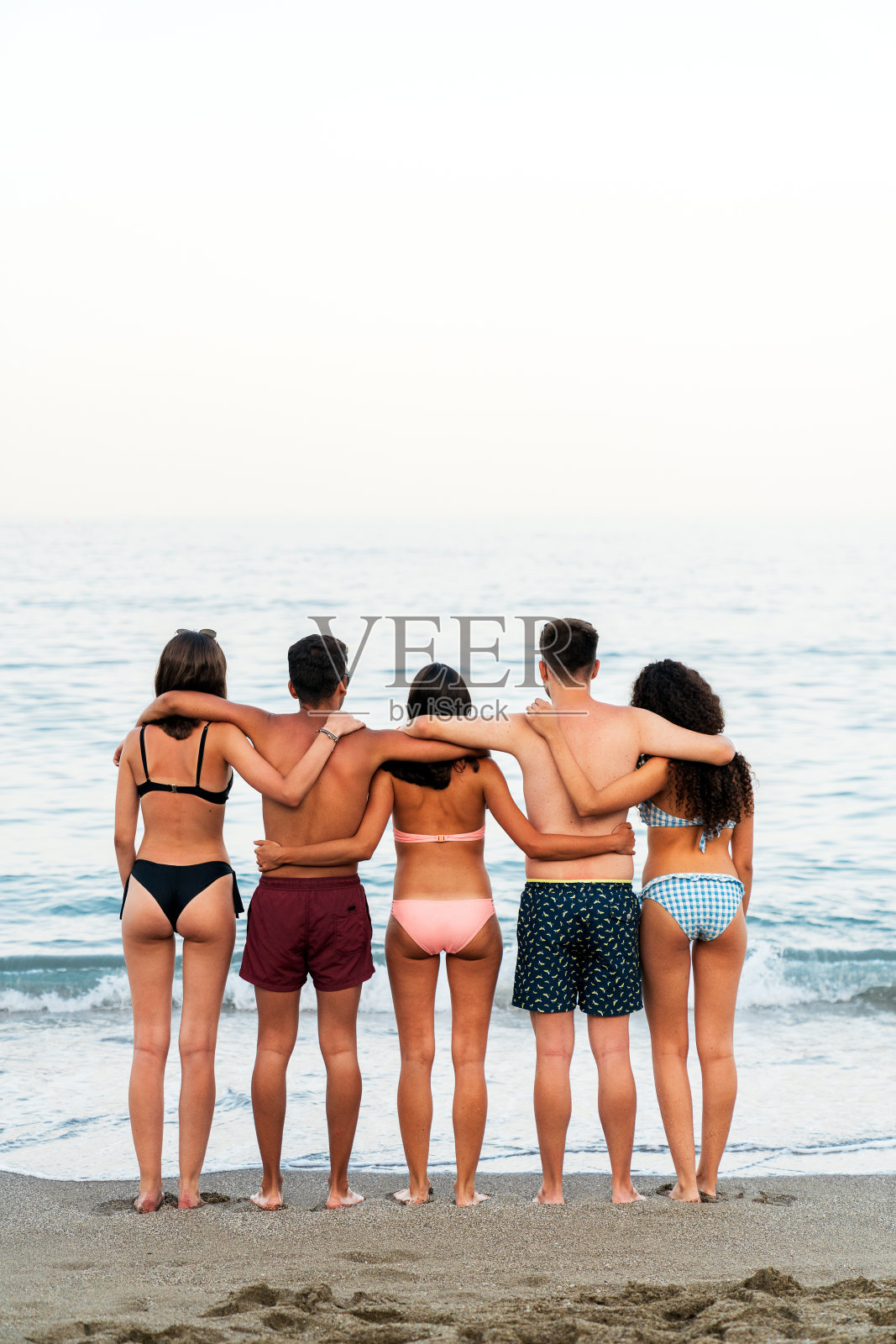 年轻的朋友们在充满泡沫的海边拥抱照片摄影图片
