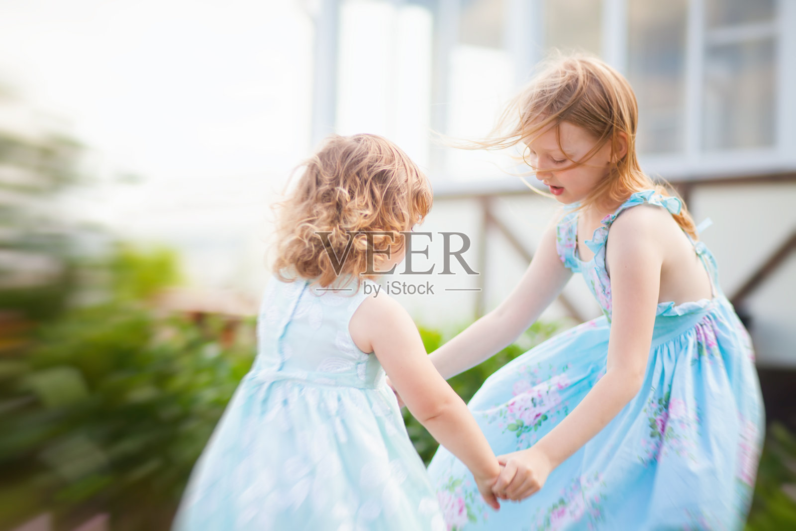 两个可爱的小女孩(朋友或姐妹)在户外一起跳舞照片摄影图片