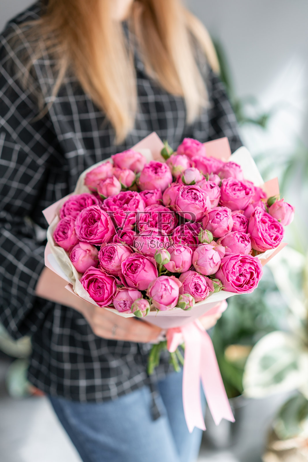 粉色和紫色的玫瑰。女人手里拿着一束美丽的混合鲜花。花店概念。英俊的新鲜的花束。花交付。照片摄影图片