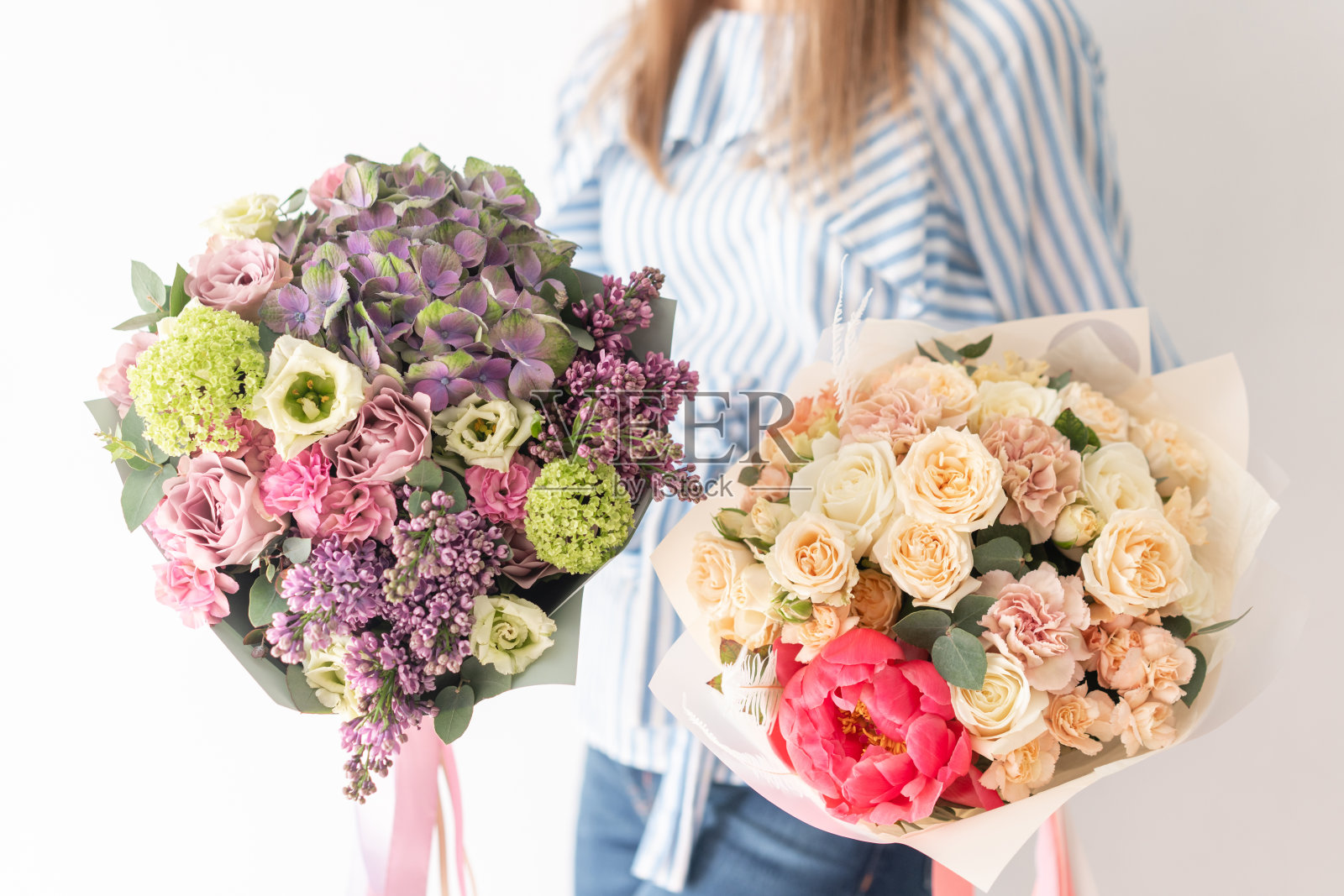 女人手里捧着两束美丽的混合鲜花。花店花匠的工作。精致柔和的颜色。新鲜切花。照片摄影图片