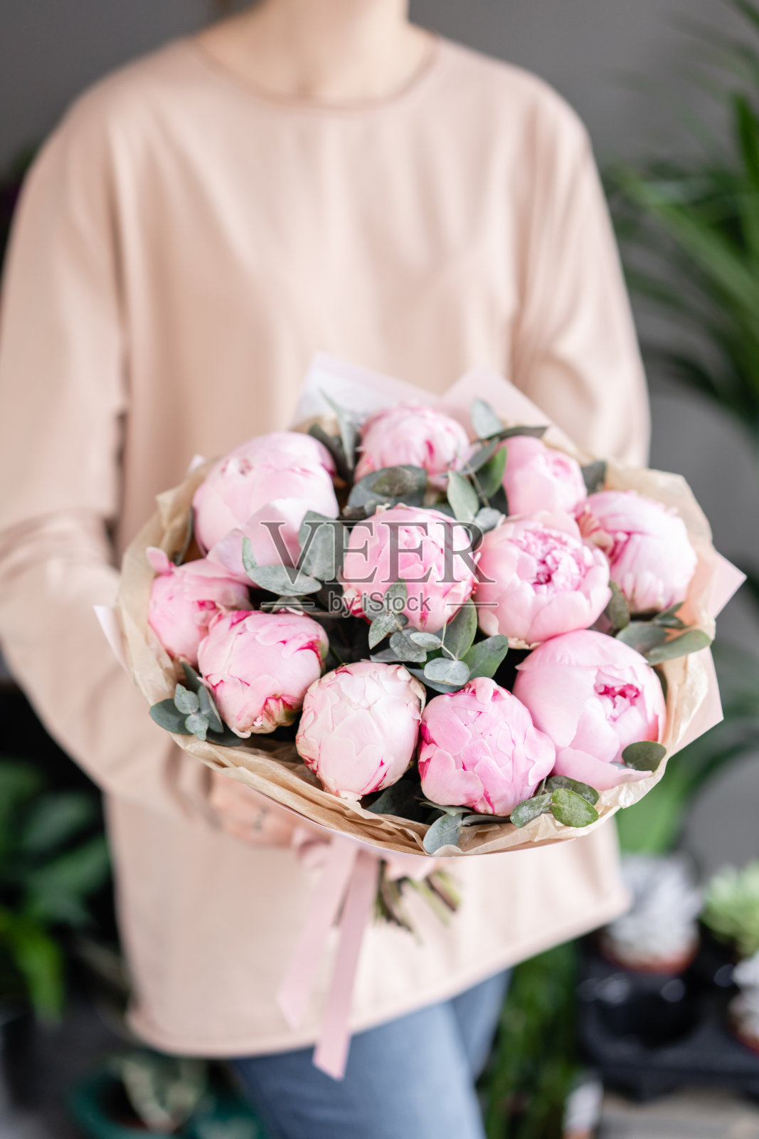 女人手里拿着粉红色的牡丹。美丽的牡丹花为目录或网上商店。花店概念。漂亮的新鲜花束。鲜花交付照片摄影图片