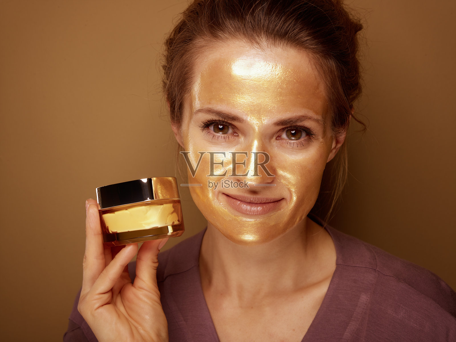 女人的金色面具显示奶油对青铜背景照片摄影图片