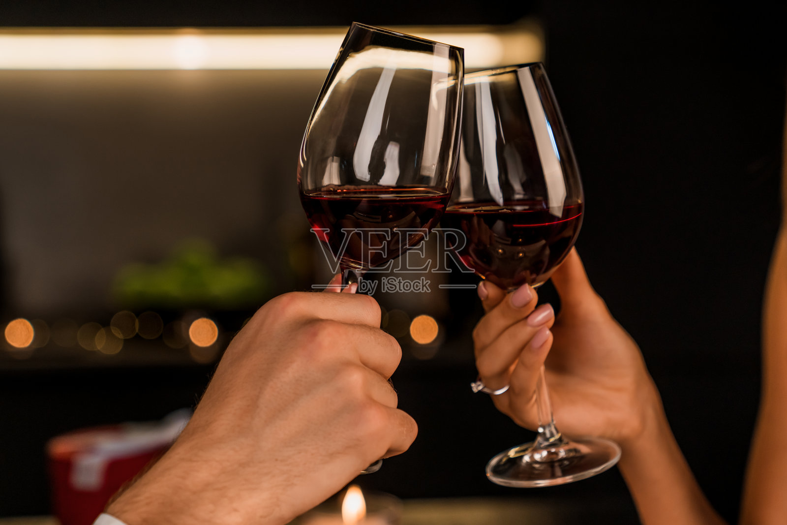 近距离拍摄的男人和女人敬酒和喝红酒从杯子上的晚餐照片摄影图片