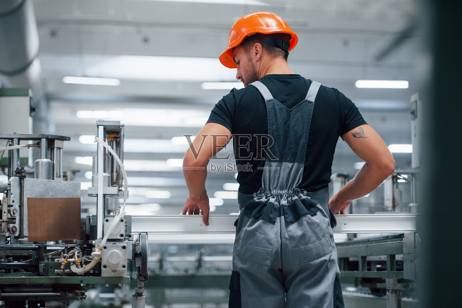 的窗口。工厂内的工业工人。戴着橙色安全帽的年轻技术员照片摄影图片