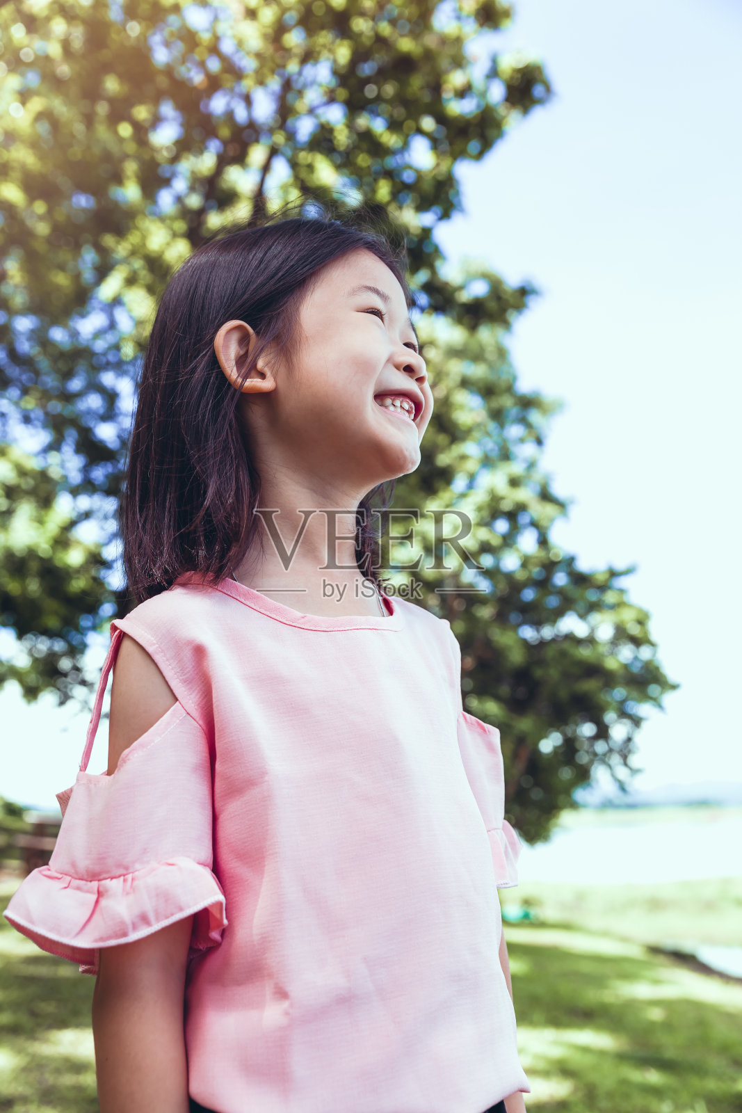 一个在公园里微笑的亚洲小女孩的肖像。照片摄影图片