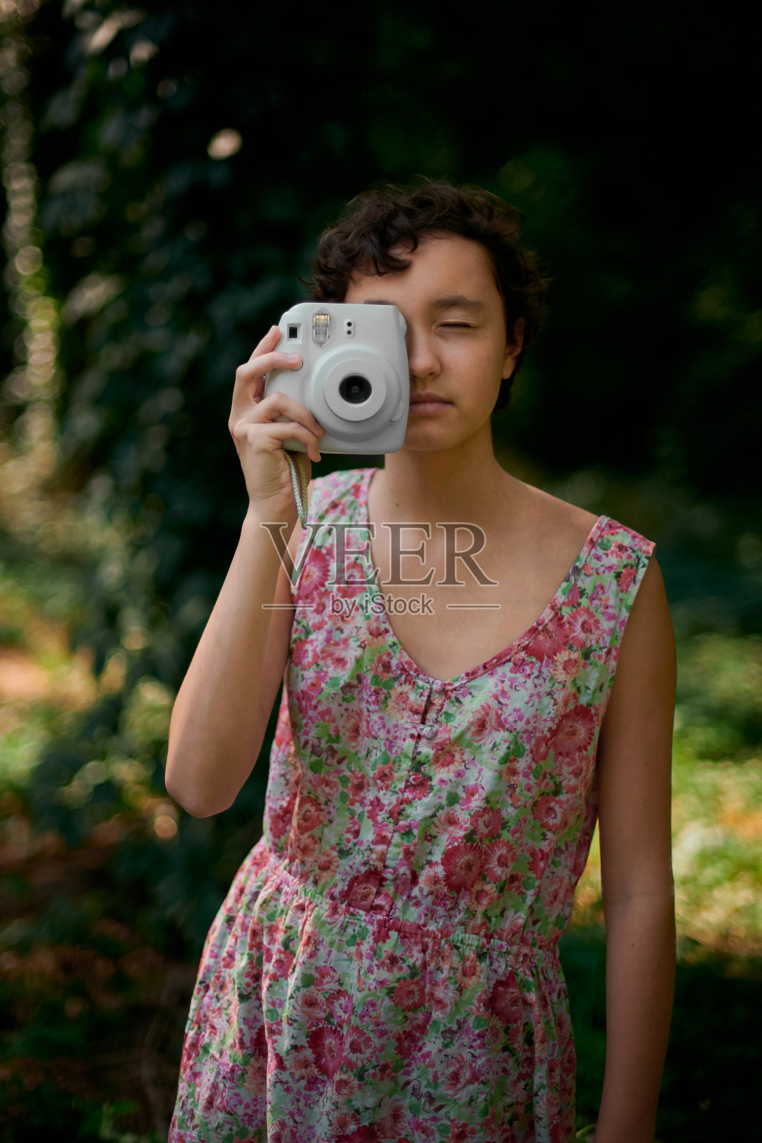 微笑的女孩在森林里用即时照相机拍照照片摄影图片