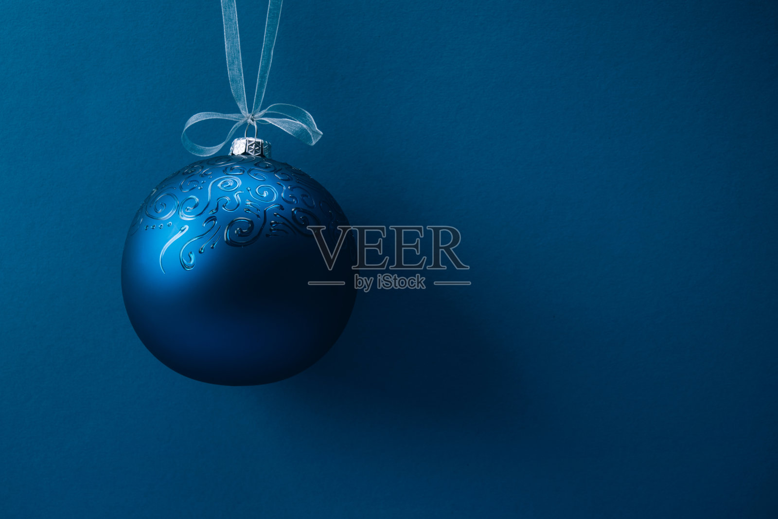 蓝色背景上挂着丝带的圣诞球。副本的空间。照片摄影图片