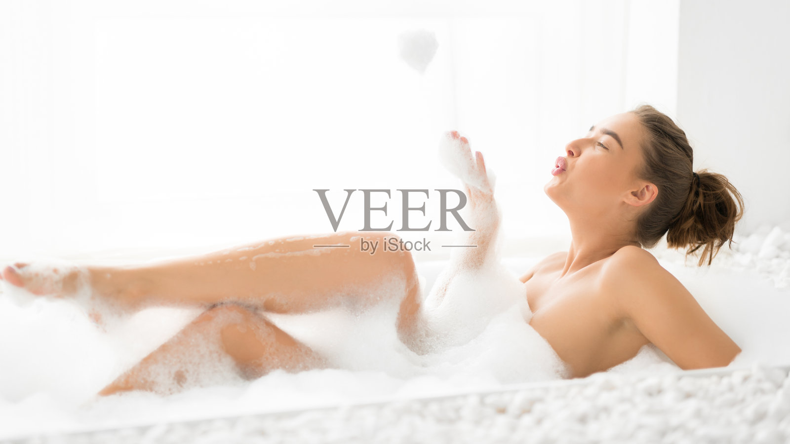 放松的女人在洗热水澡和玩泡沫照片摄影图片