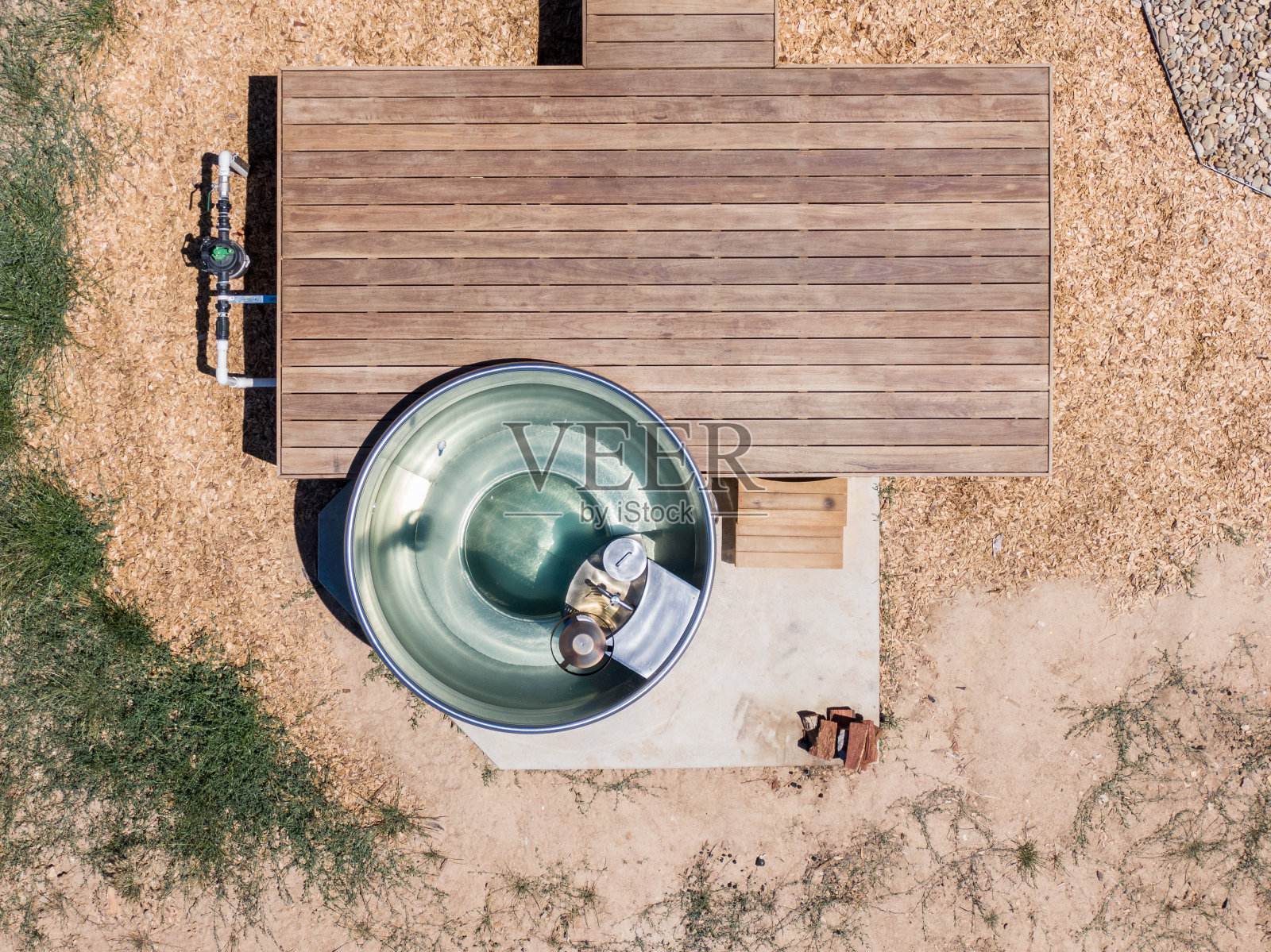 这是澳大利亚新南威尔士州贡达盖一间豪华豪华豪华小屋的鸟瞰图，里面有烧木头的不锈钢户外热水浴缸和带楼梯的木制露台。照片摄影图片