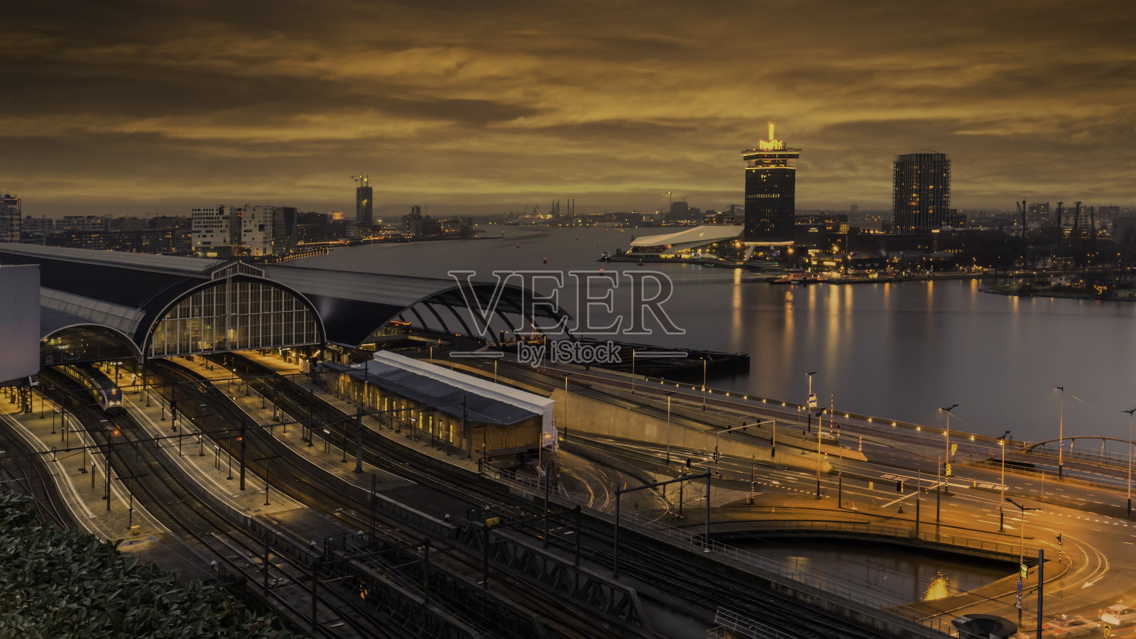 阿姆斯特丹火车站和阿姆斯特尔河的夜景，荷兰照片摄影图片