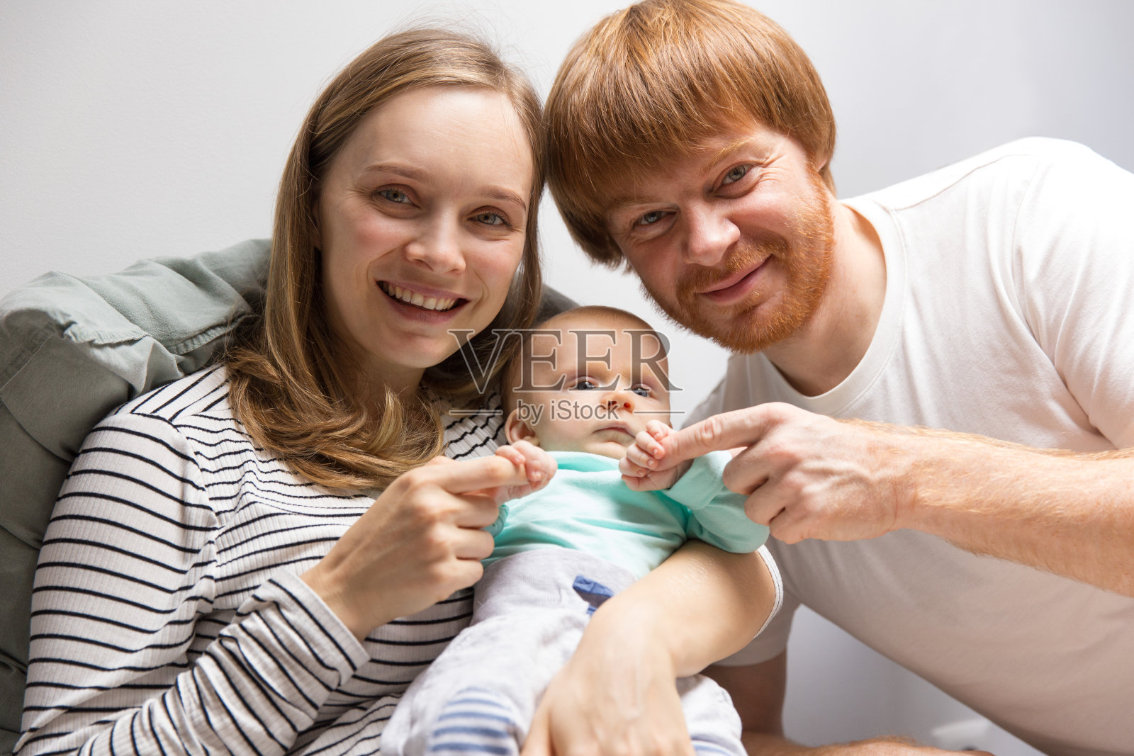 积极的父母抱着红头发的婴儿照片摄影图片