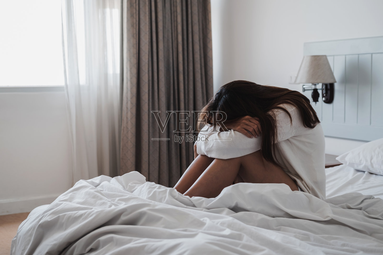 孤独的年轻女人沮丧和紧张，双手抱头坐在黑暗的卧室里，消极情绪的概念照片摄影图片