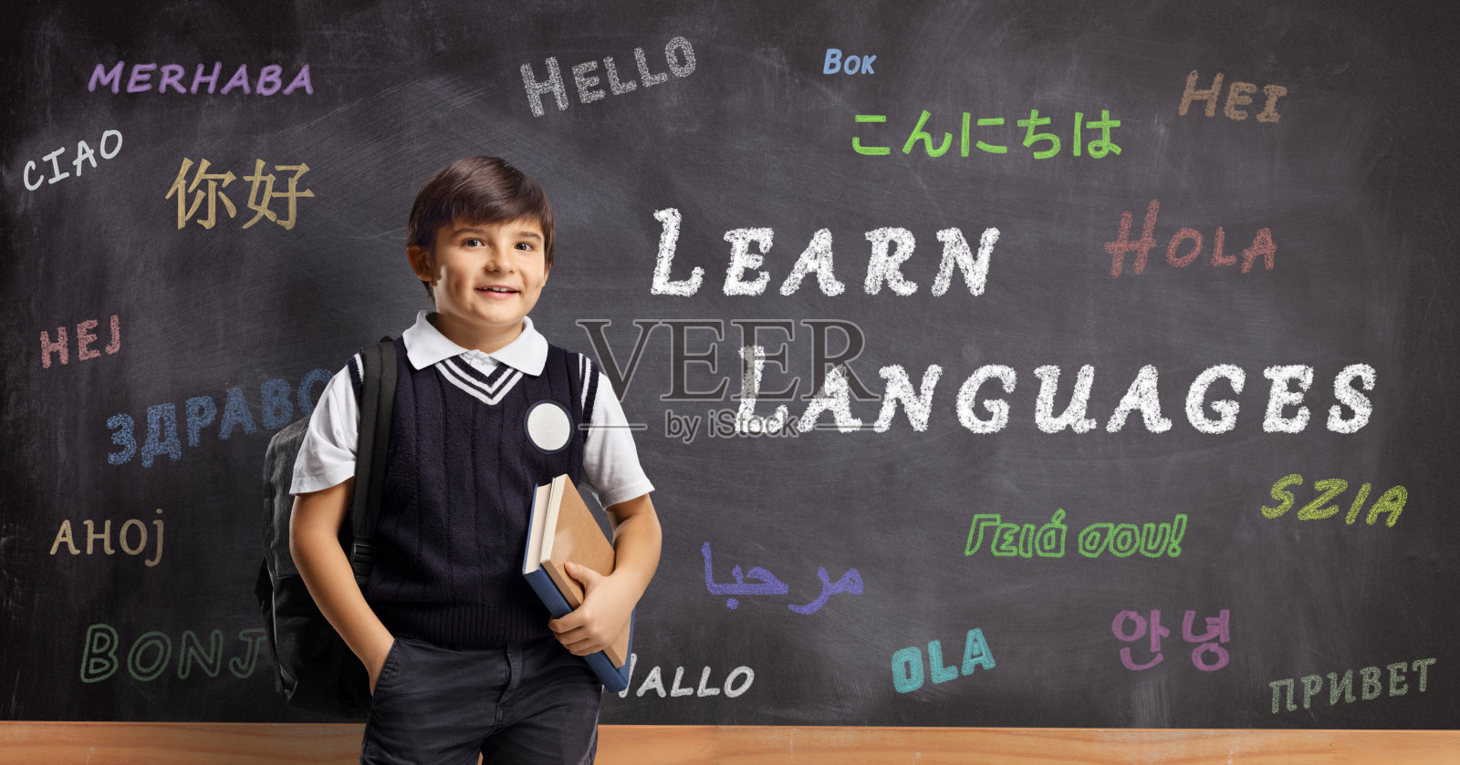 一个男生在黑板前用不同的语言写着“你好”和课文学习语言照片摄影图片
