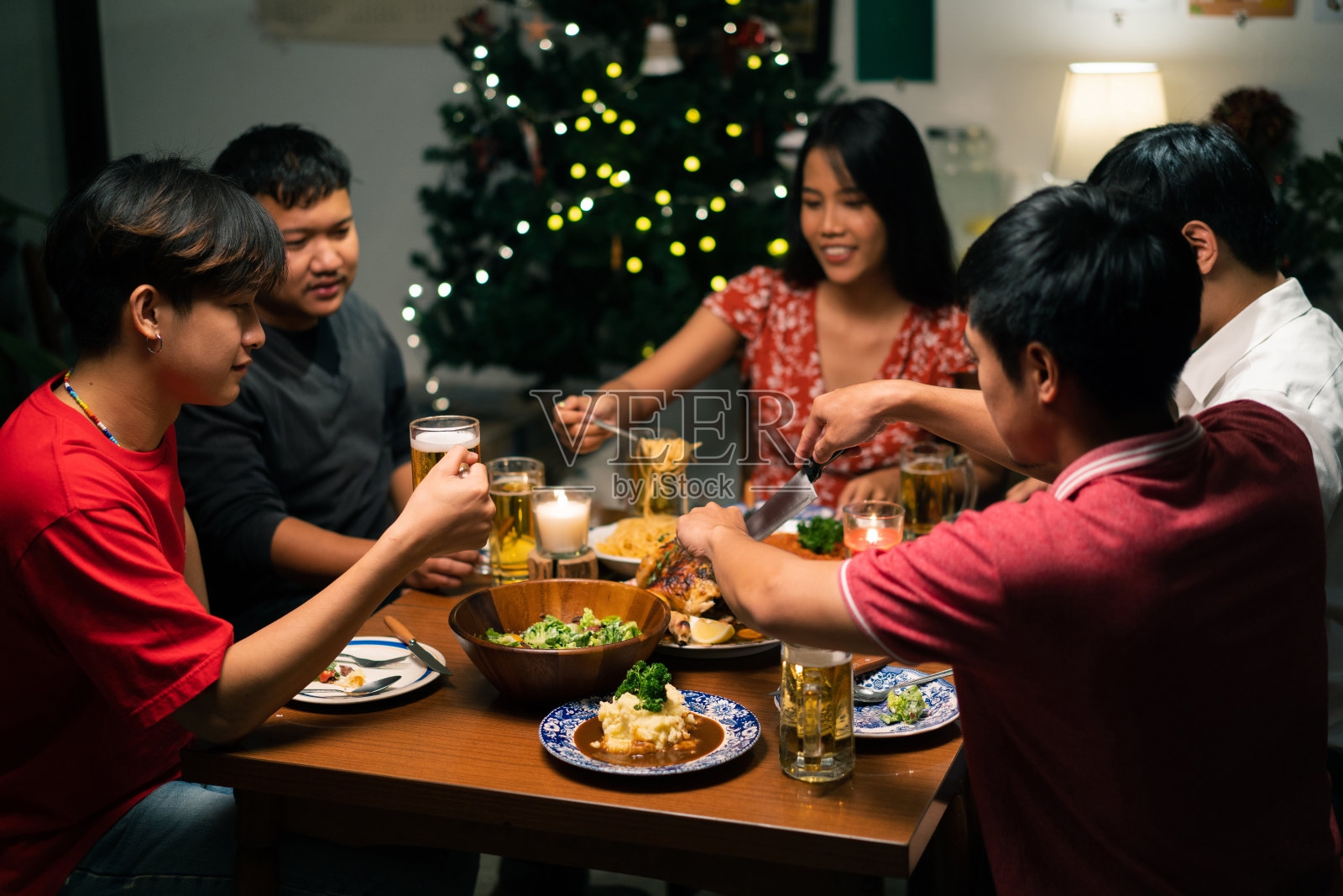 一群亚洲人在家里举行晚宴并喝啤酒。照片摄影图片