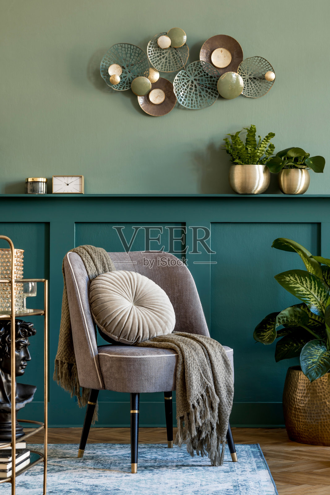时尚现代的客厅组合设计灰色扶手椅，金色酒柜，植物和优雅的个人饰品。带架子的灰色墙板。现代家居装饰。模板。照片摄影图片