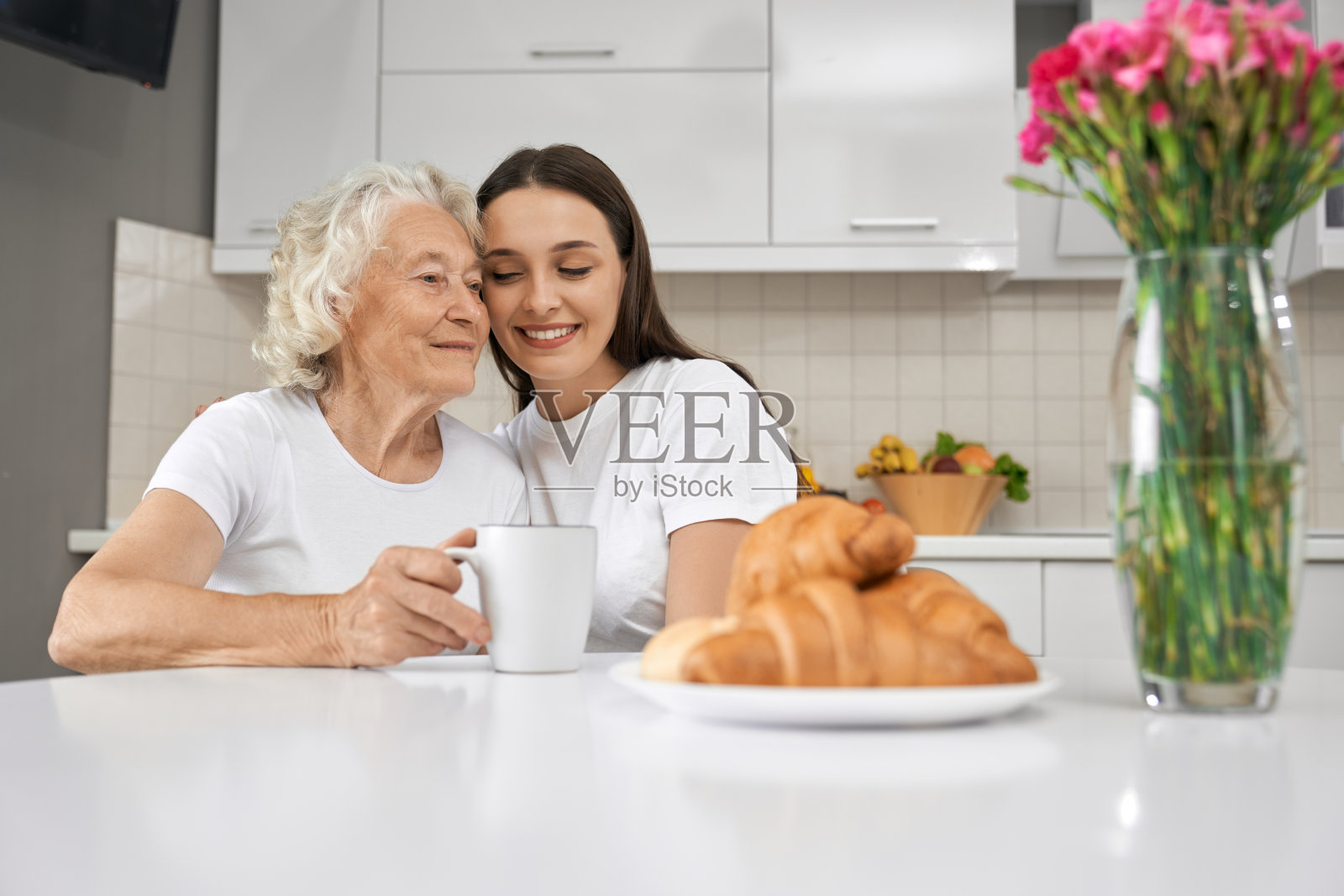 小女孩在厨房里拥抱奶奶。照片摄影图片