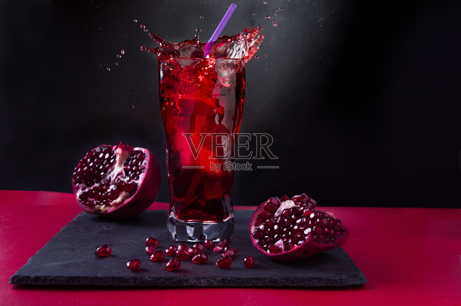 石榴汁。喷在玻璃杯里。果汁和石榴水果。照片摄影图片