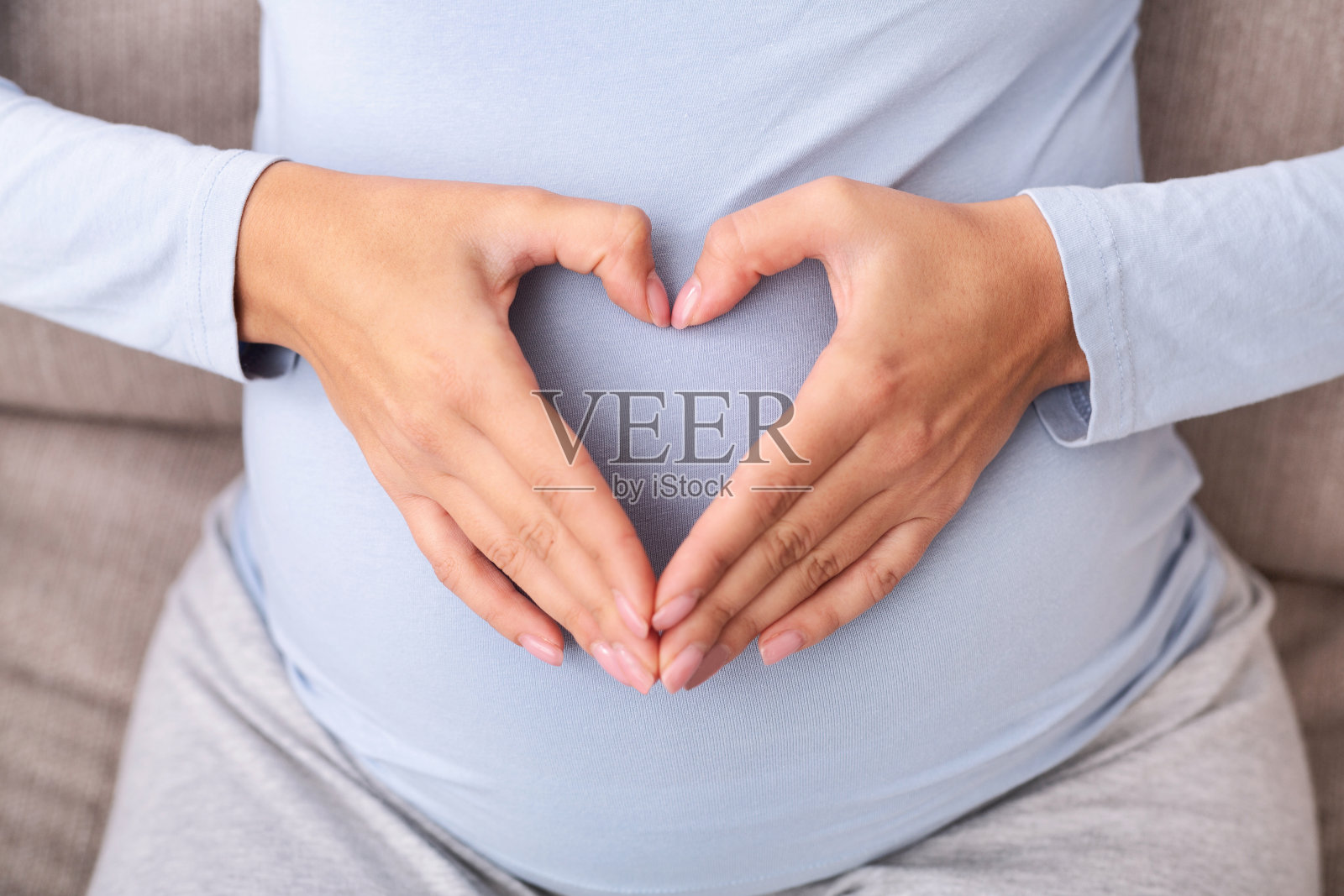 不可辨认的孕妇手在腹部形成心脏，俯视图照片摄影图片
