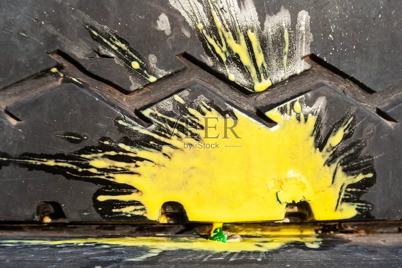 一辆旧汽车轮胎上有锯齿形胎面花纹，被撞的彩弹溅出黄色油漆照片摄影图片