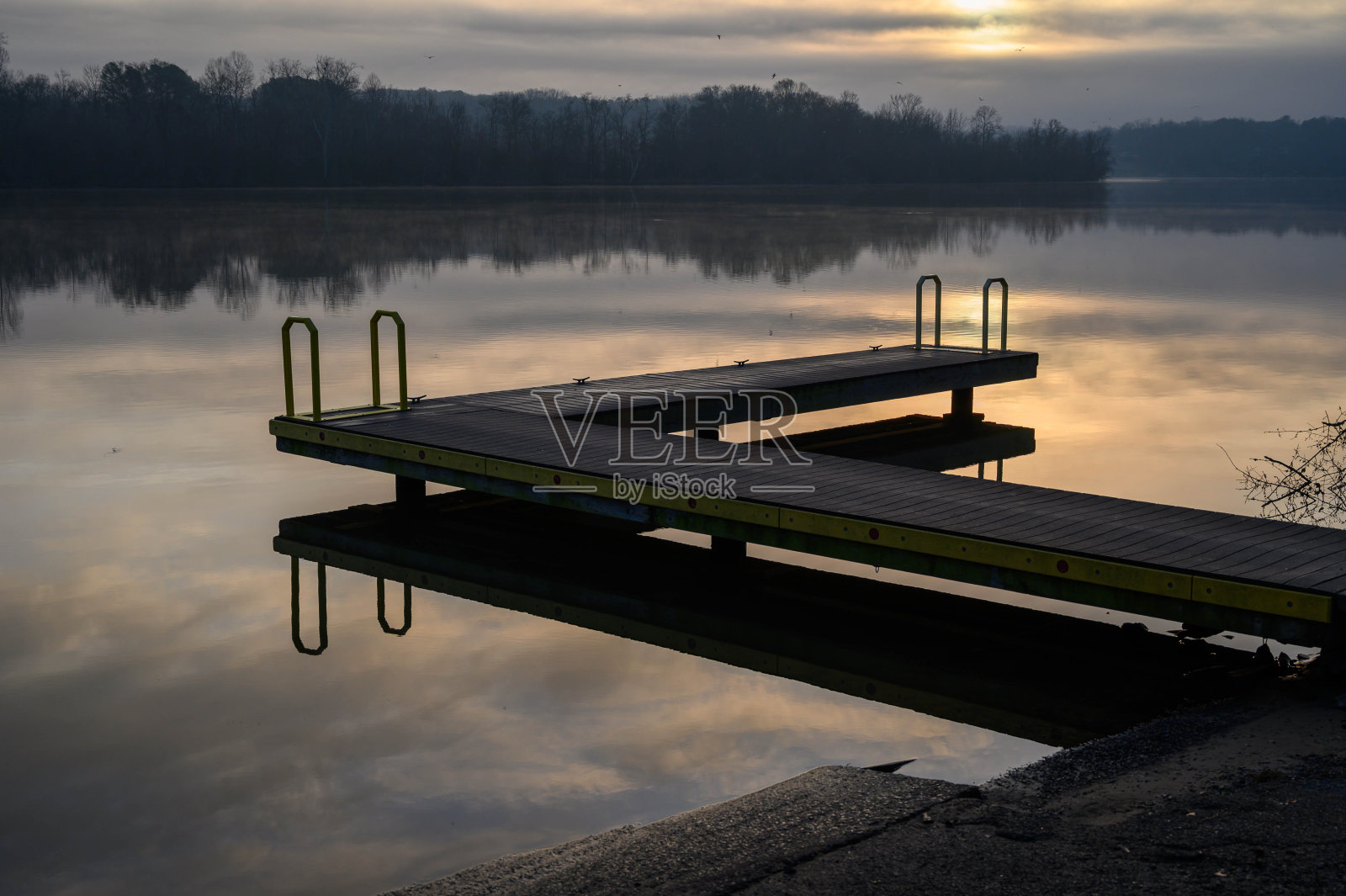 在一个平静的日出早晨，小船停靠在河面上照片摄影图片