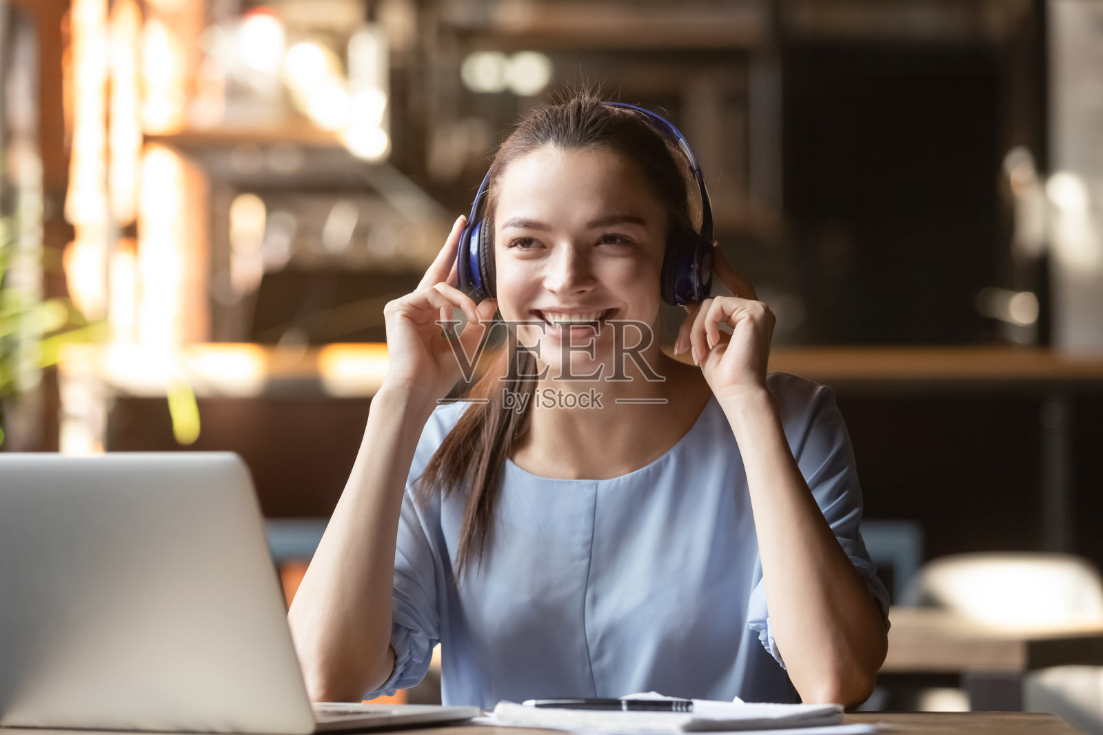 快乐的年轻女子戴着耳机在咖啡馆听音乐照片摄影图片