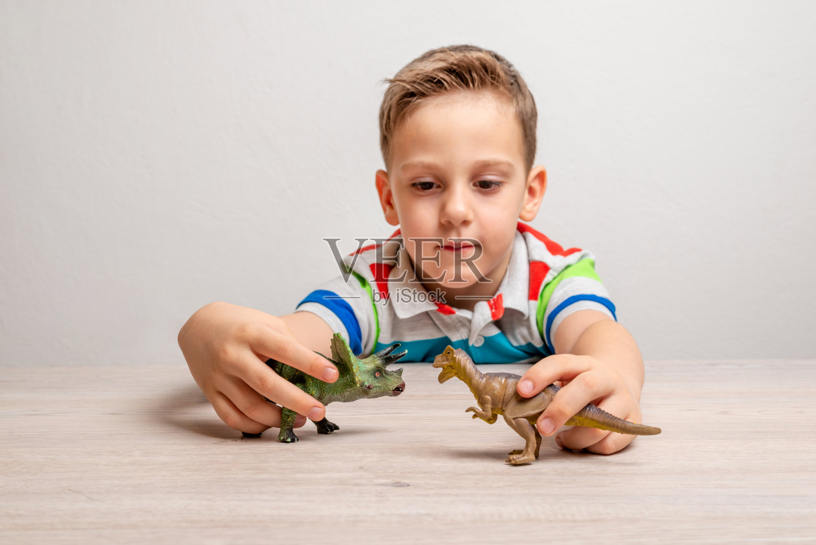 男孩拿着恐龙玩具。通过游戏培养儿童注意力的概念照片摄影图片