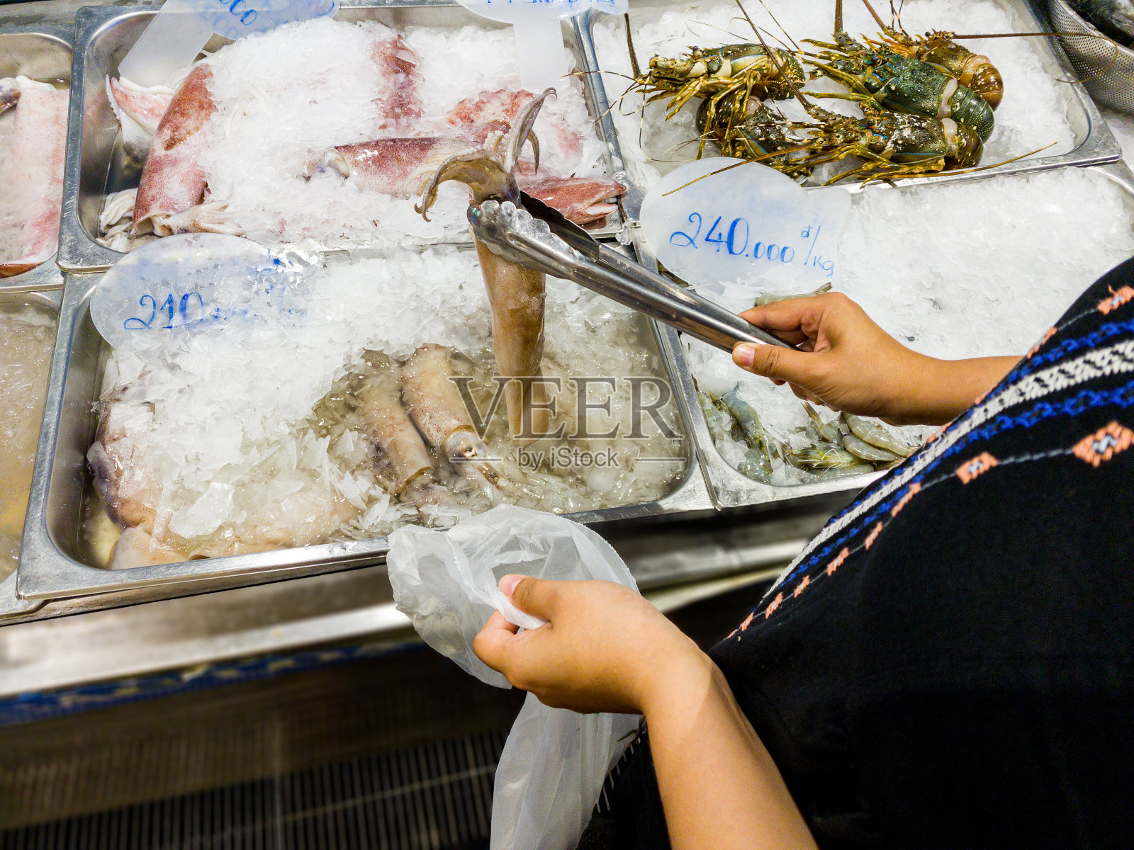 在越南的冷冻海鲜市场买鱿鱼的女人照片摄影图片