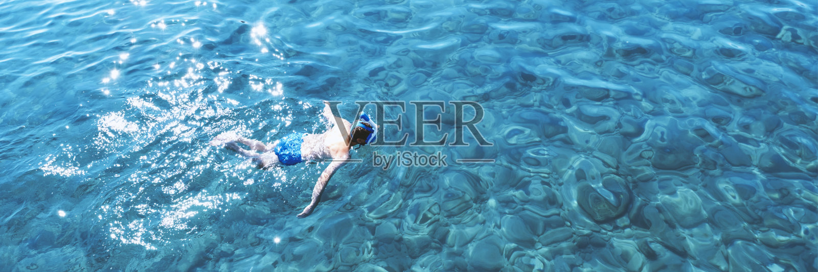 年轻人穿着泳衣躺在蓝色的水中，鸟瞰照片摄影图片