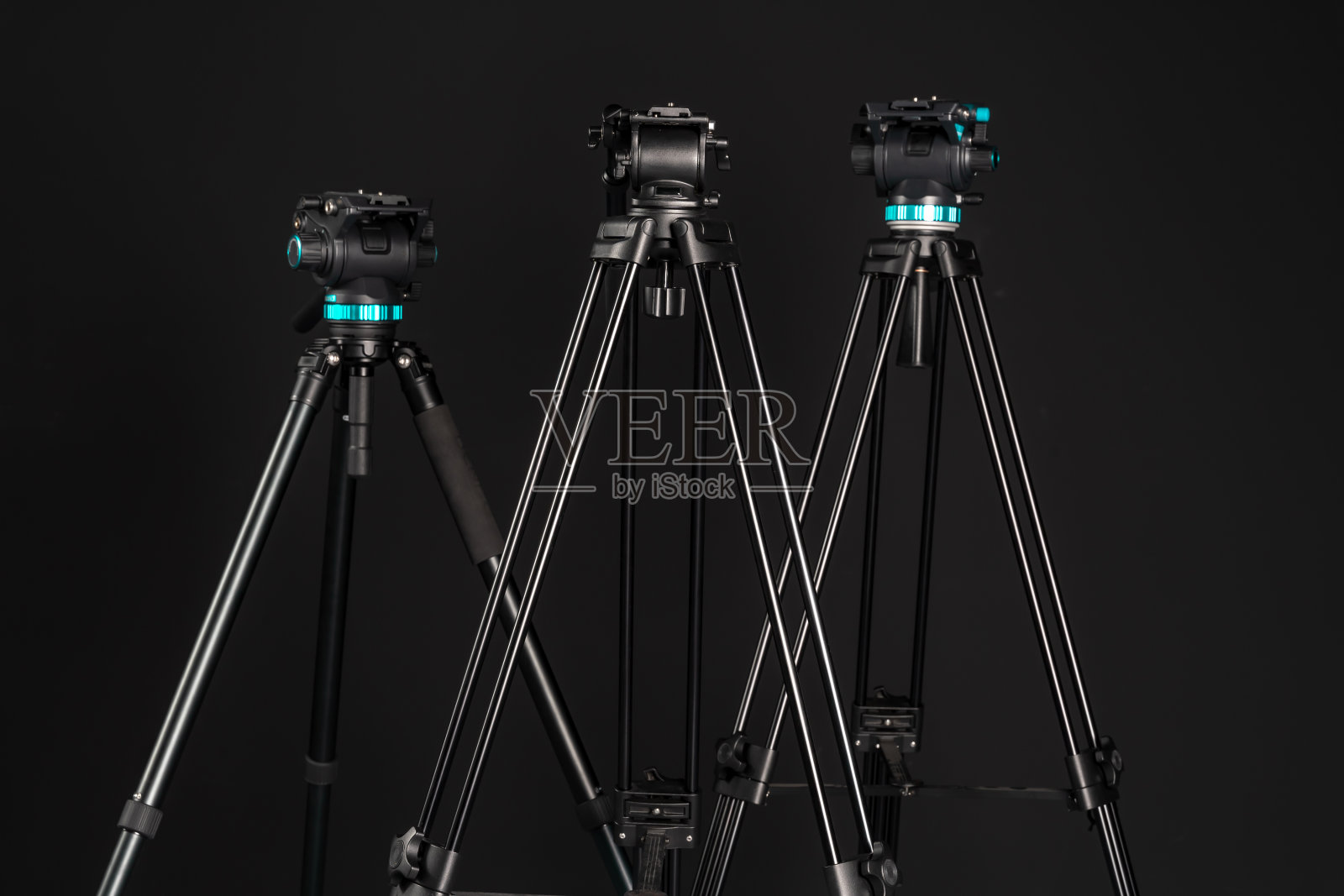 三个专业的视频相机三脚架与相机头和释放板上的黑色工作室背景照片摄影图片