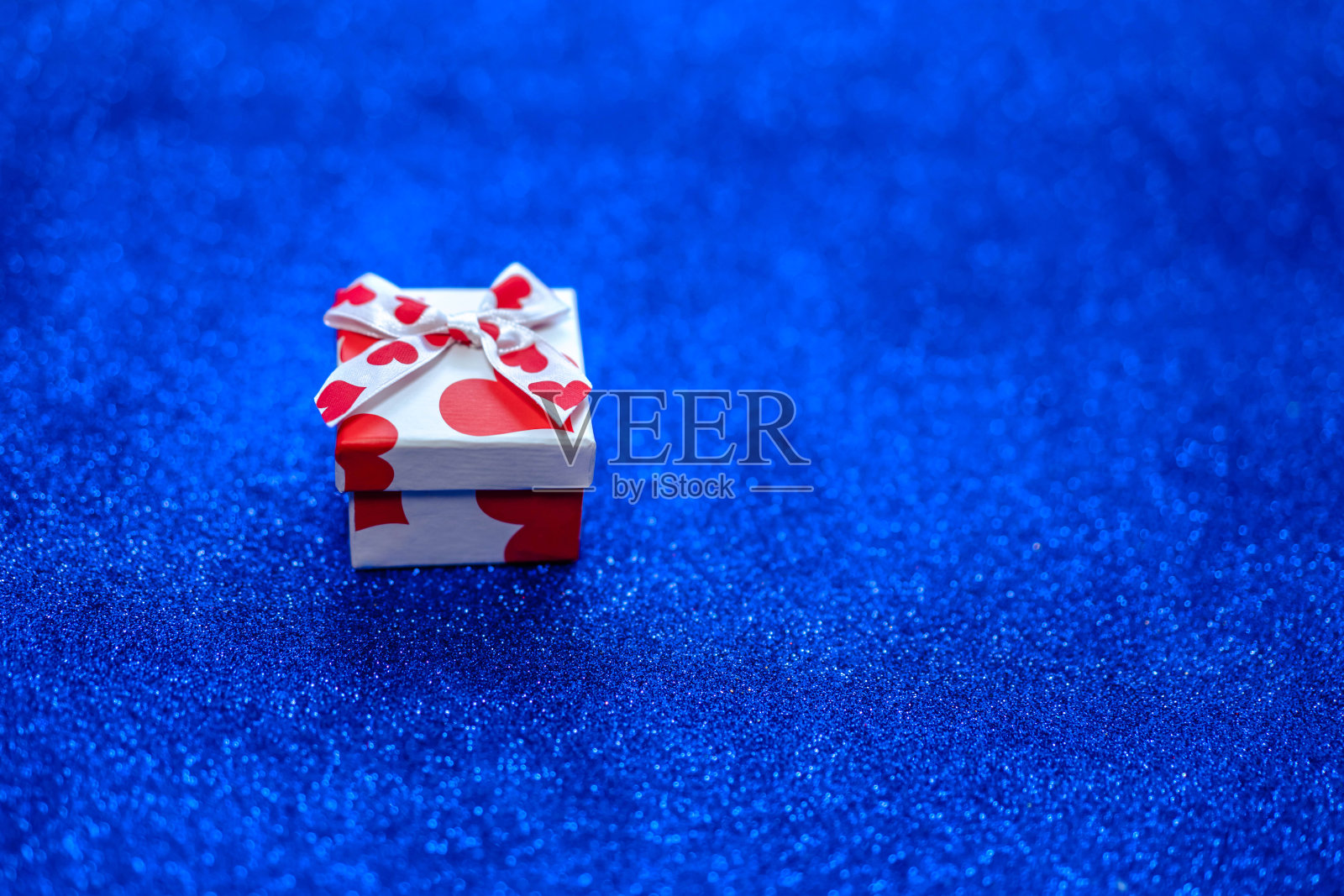 礼物盒与心在一个经典的蓝色闪光背景。照片摄影图片