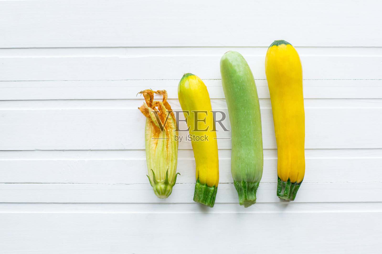 绿色和黄色的西葫芦。新鲜蔬菜。在一张白色的木桌上。从以上观点。照片摄影图片