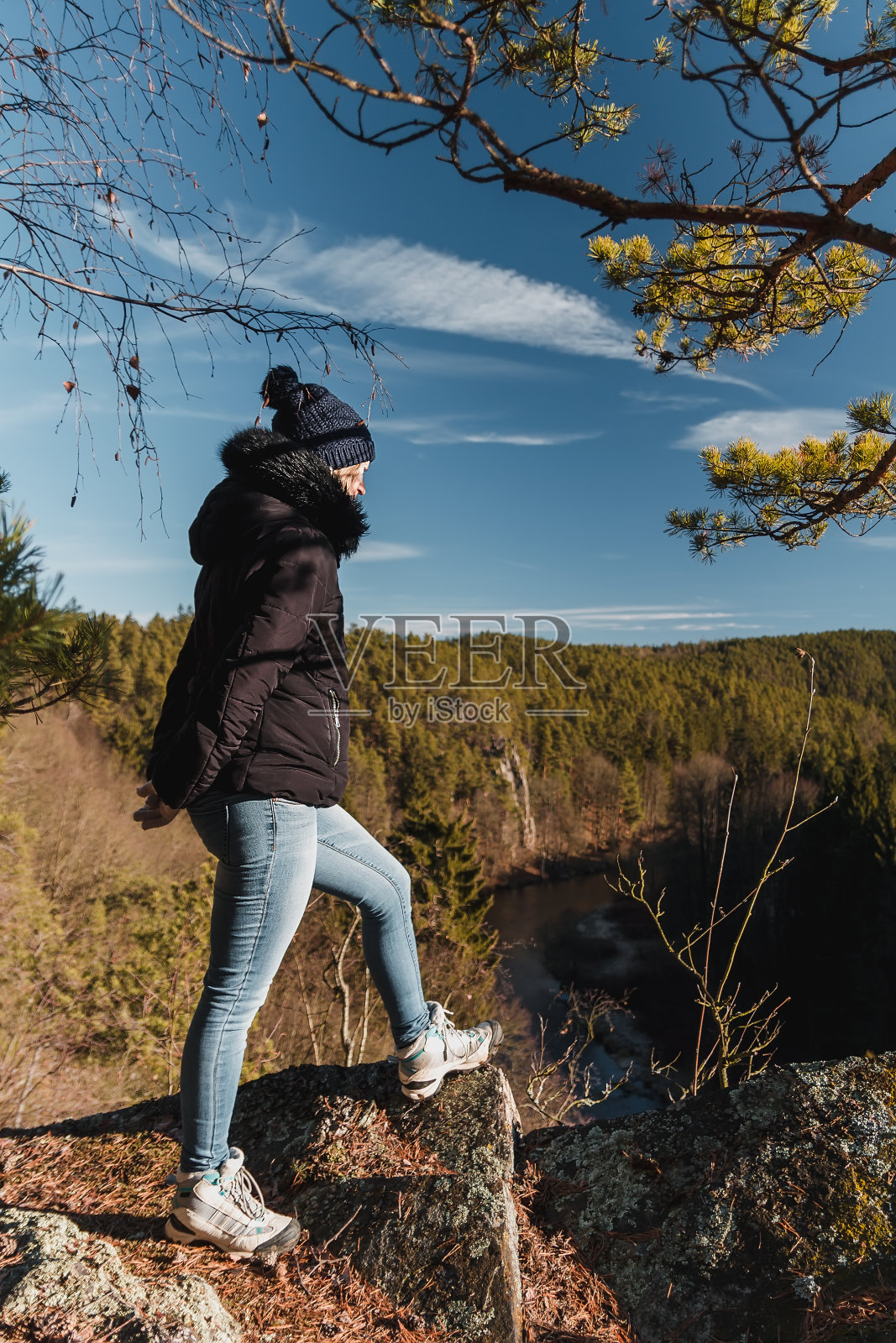 美丽的年轻女子站在岩石与森林和河流的山谷照片摄影图片