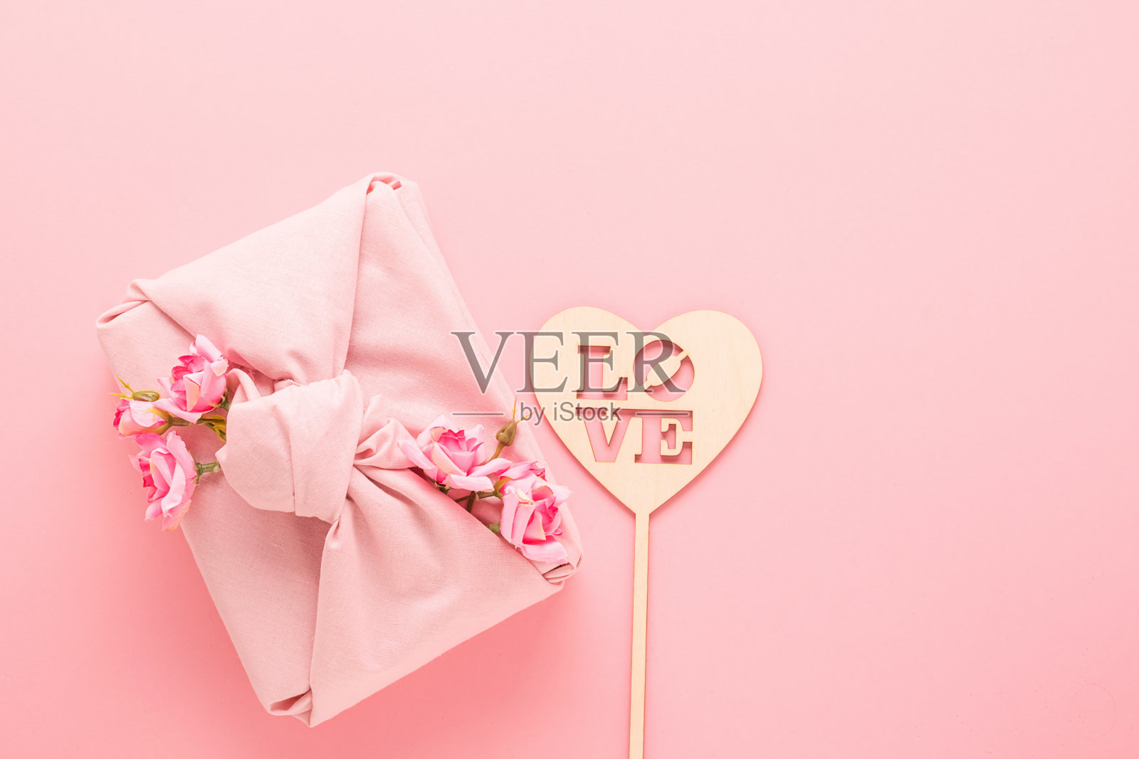 节日礼物包装的furroshiki风格的面料和一个心形的天然材料与热爱粉色的背景。照片摄影图片