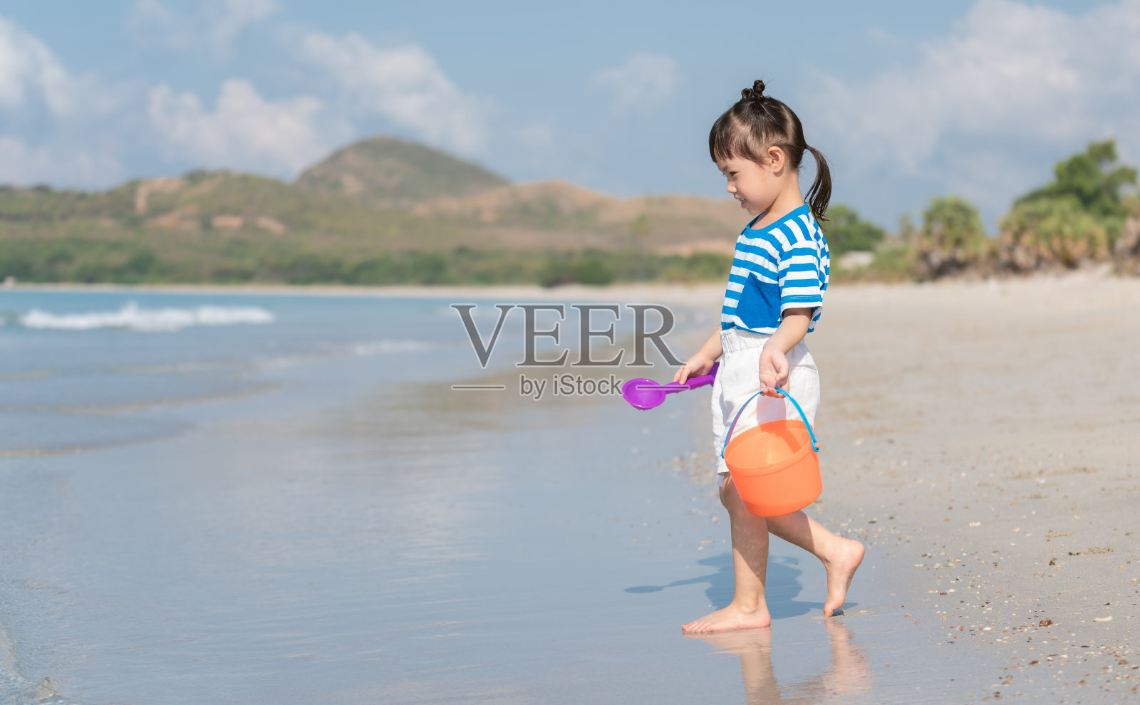 亚洲小女孩在沙滩上玩沙子。三岁的孩子玩沙玩具。幸福的家庭的概念照片摄影图片