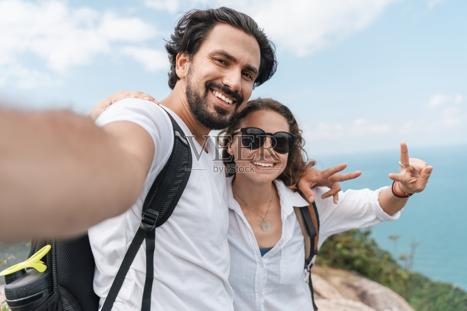 快乐美丽的年轻夫妇旅行者男人和女人在山顶上的海景自拍。浪漫的旅行,度蜜月,照片摄影图片